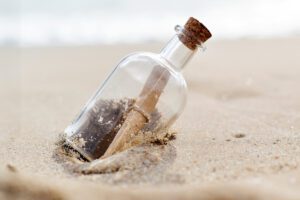 Glass bottle with a message inside resting on a beach