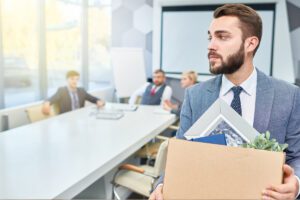 Professional walking away from desk holding box of personal items